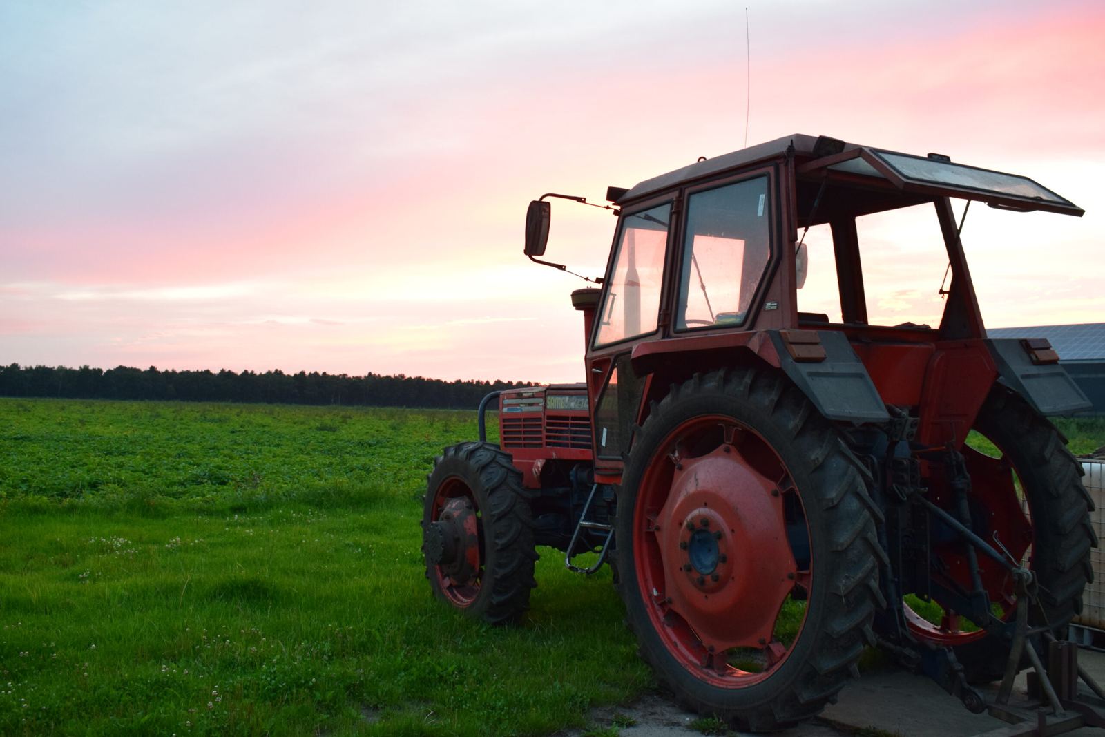 Rode trekker in het veld bij zonsondergang